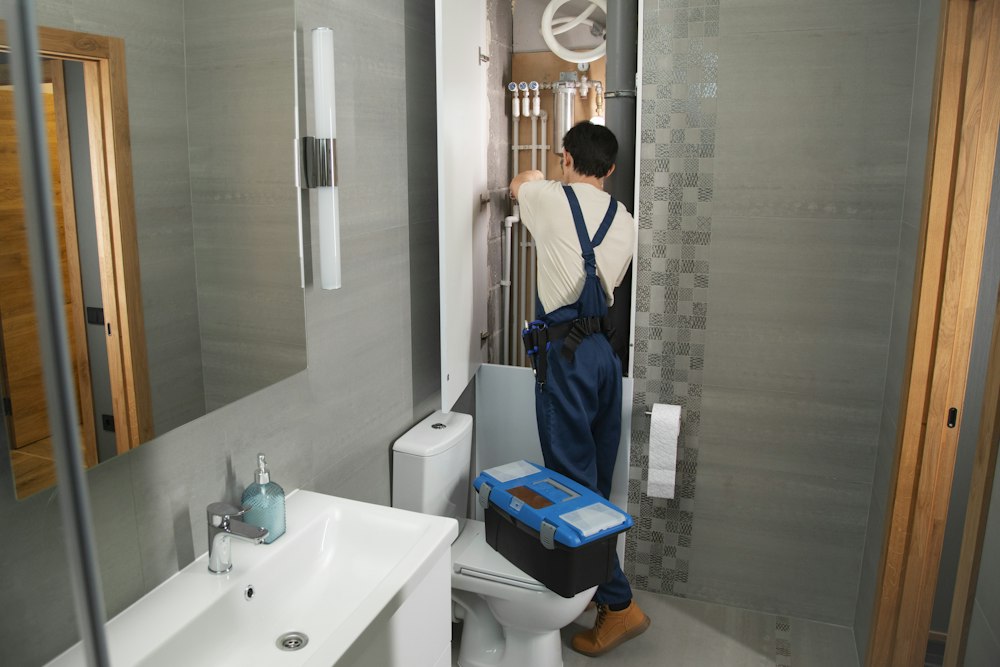 Plumber working on exposed bathroom pipework
